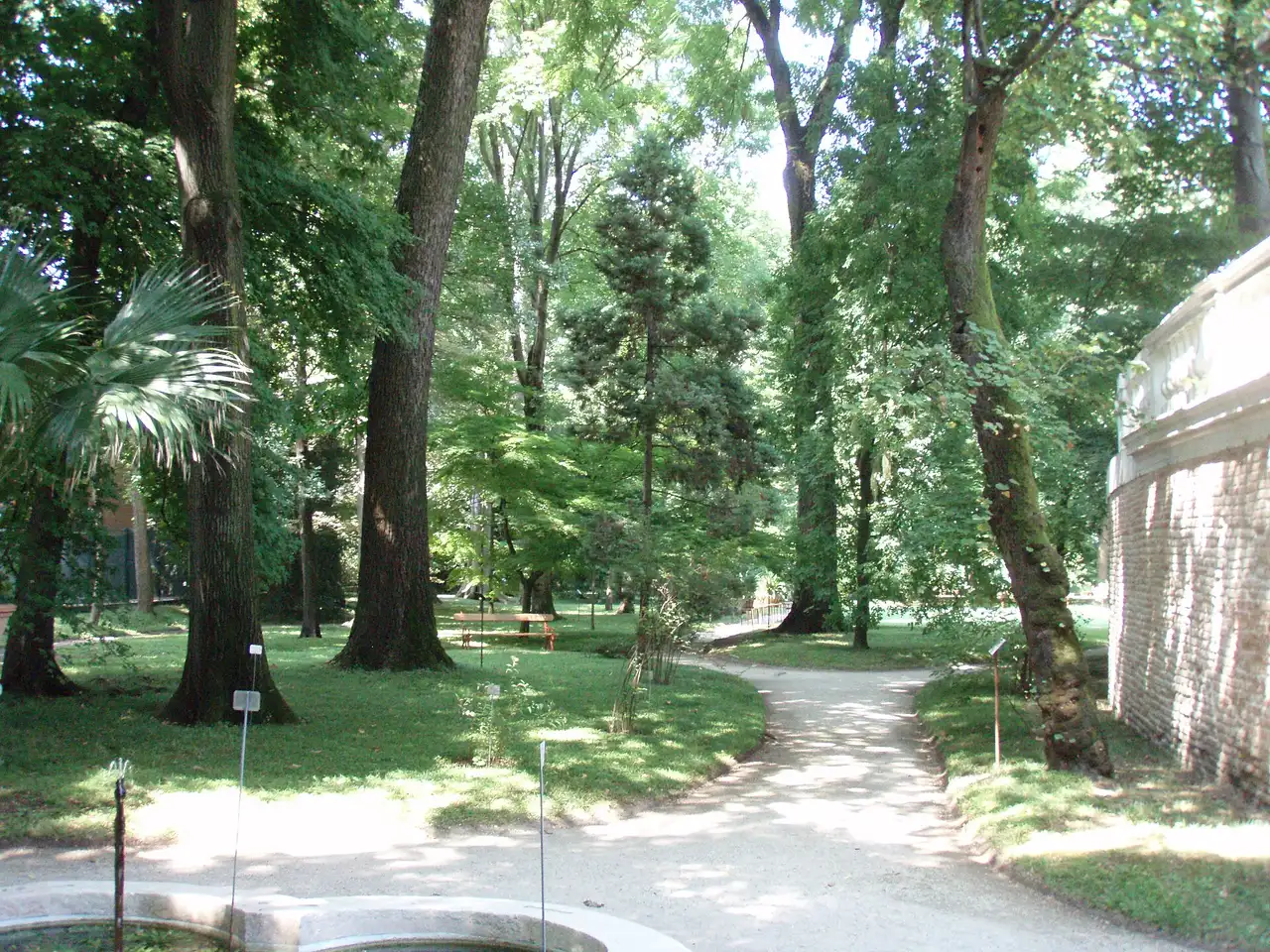 Round renaissance plot and fountain of the Padua botanical garden with the modern greenhouses behind